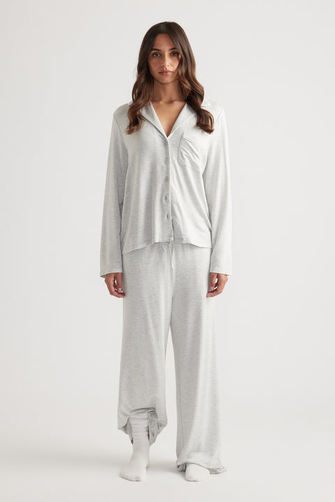 Woman wearing light grey sleep button through shirt with relaxed fit and matching wide leg lounge pants for easy comfort