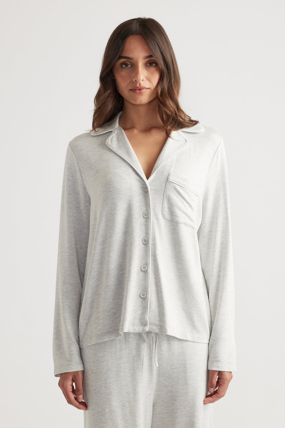 Woman wearing light grey sleep button through shirt with matching relaxed pants for cozy loungewear style