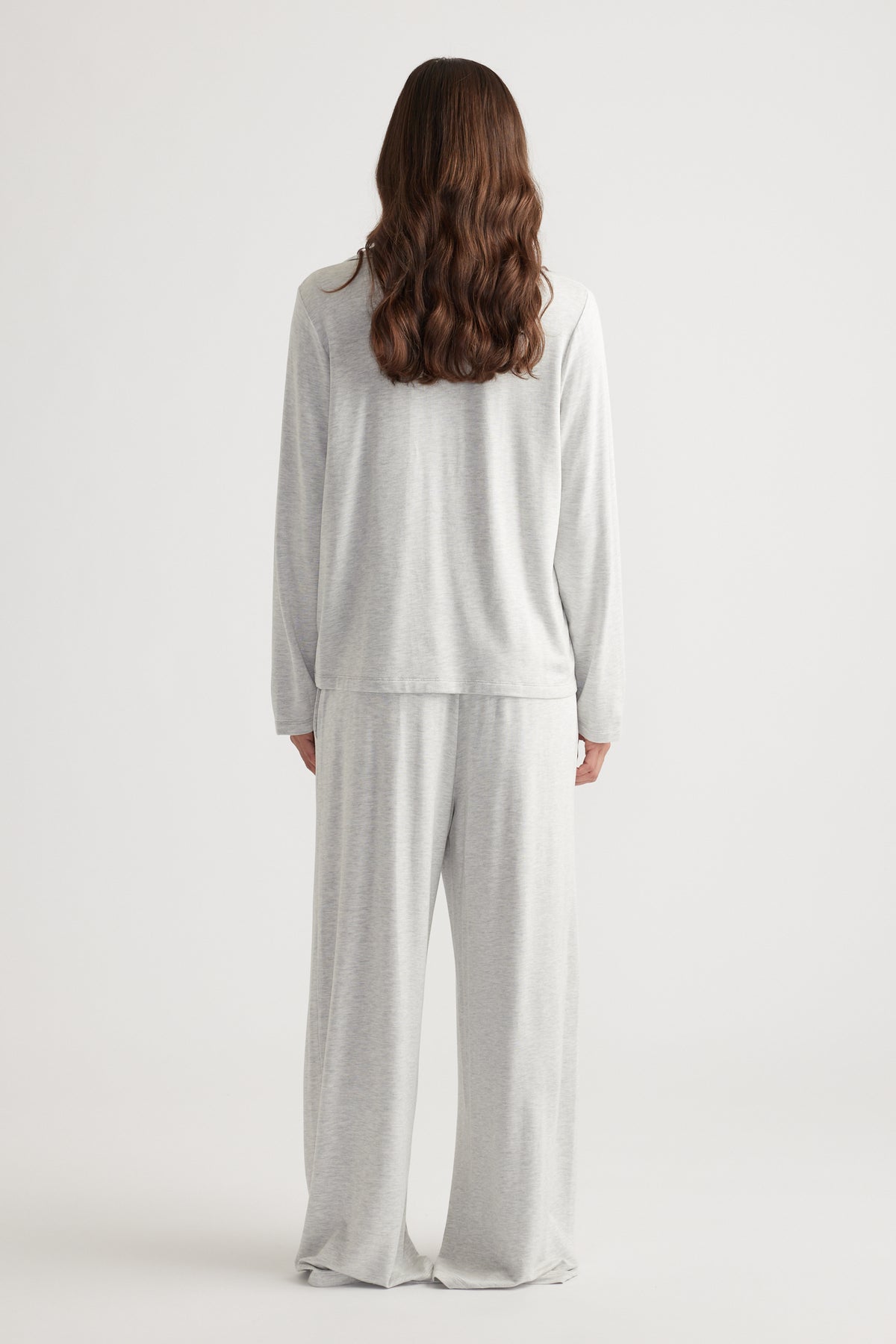 Woman wearing light grey soft lounge set with relaxed fit long sleeve top and wide leg pants for cozy comfort