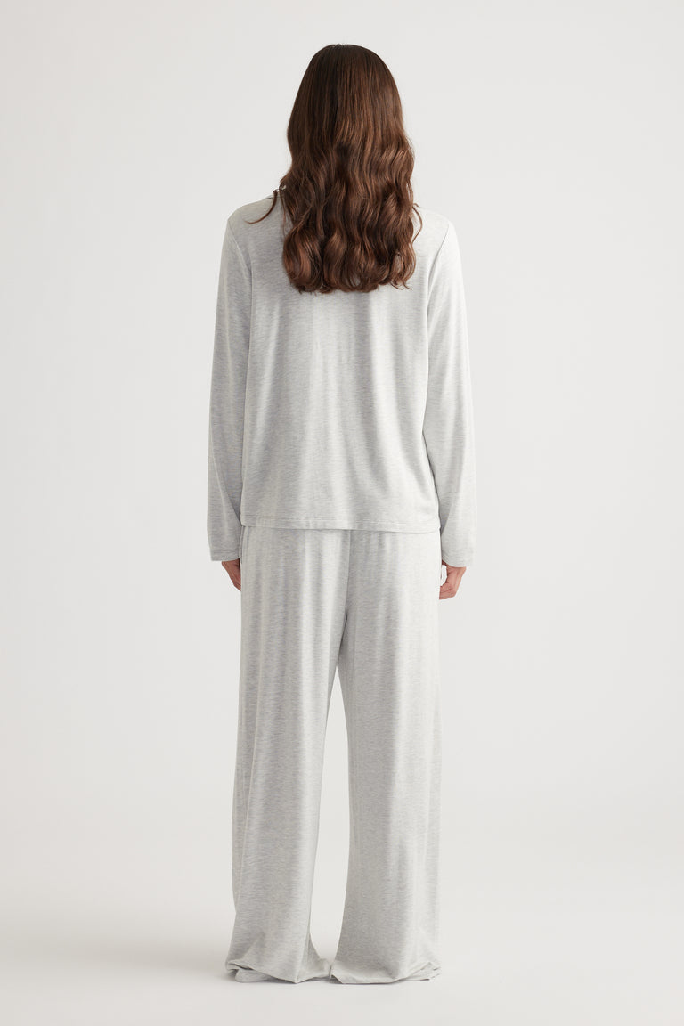 Woman wearing light grey soft lounge set with relaxed fit long sleeve top and wide leg pants for cozy comfort