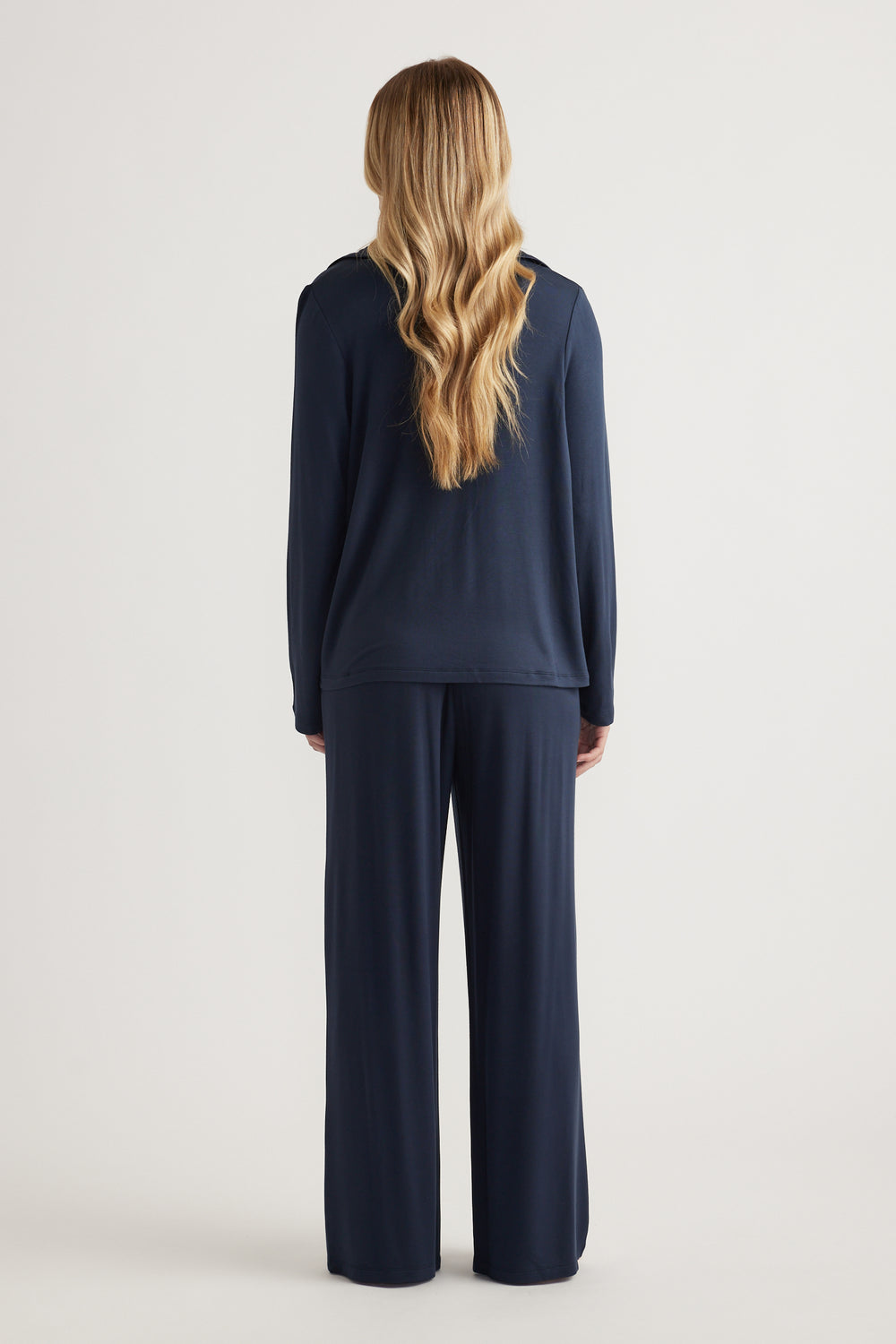 Woman wearing a navy long-sleeve sleep shirt with matching wide-leg lounge pants