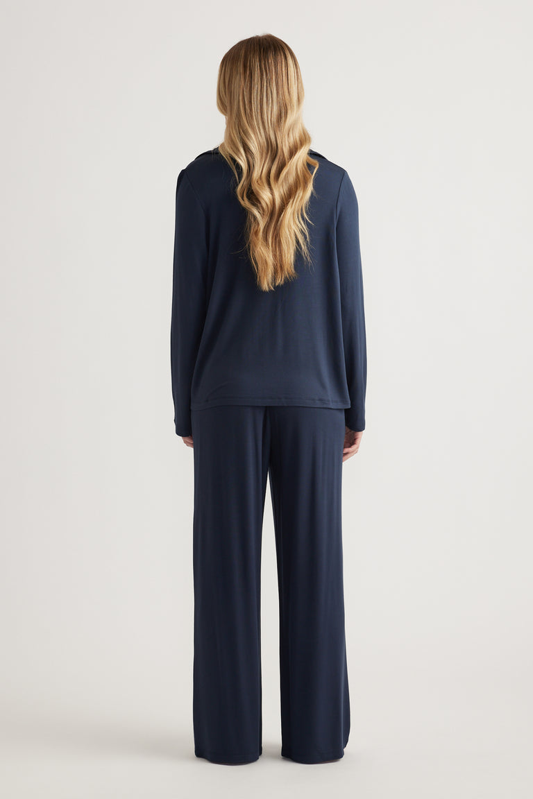 Woman wearing a navy long-sleeve sleep shirt with matching wide-leg lounge pants