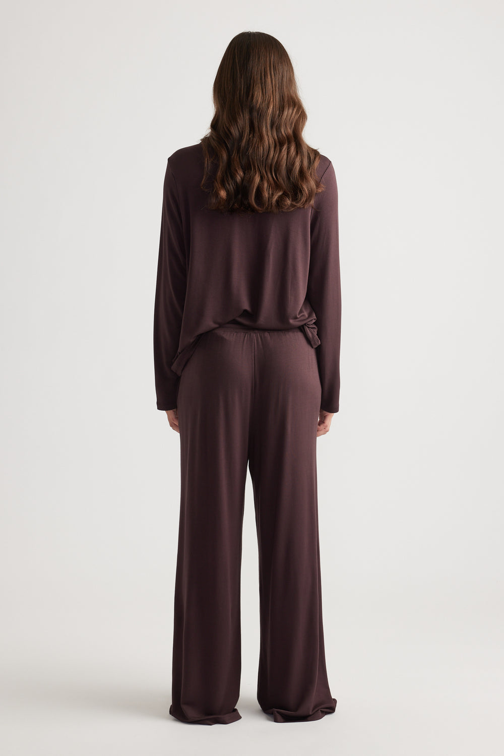 Woman wearing relaxed dark brown wide leg sleep jersey pants with matching long sleeve top for comfortable loungewear style