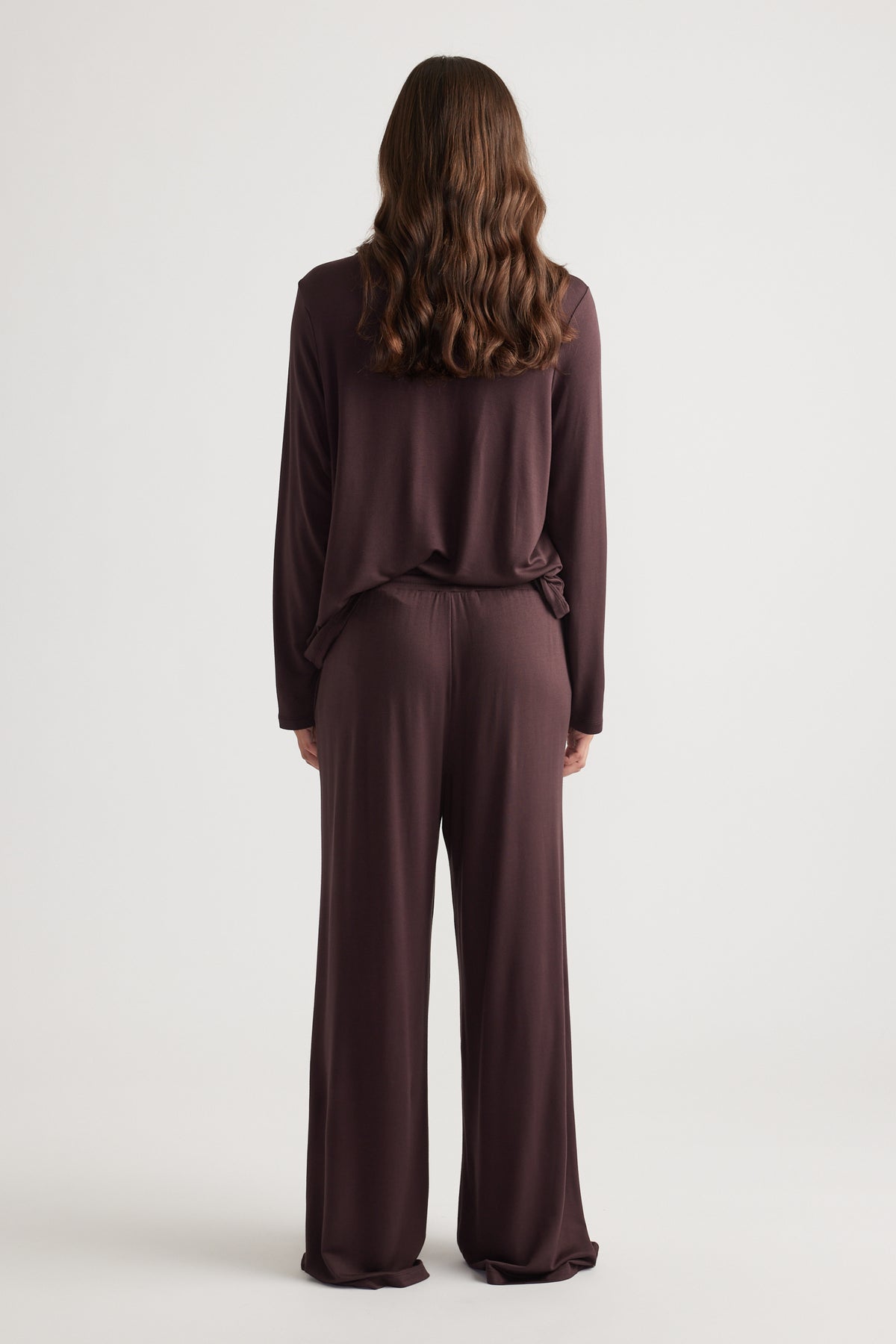 Woman wearing relaxed dark brown wide leg sleep jersey pants with matching long sleeve top for comfortable loungewear style