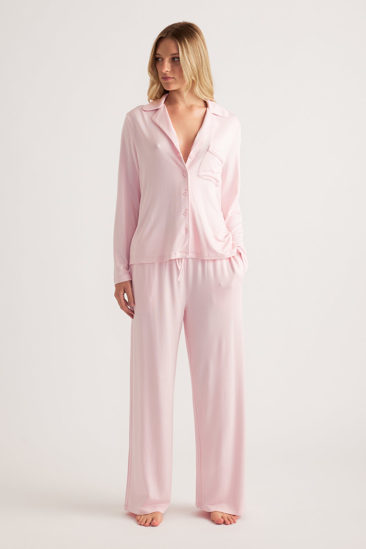 Woman wearing a pale pink button front sleep shirt with wide leg pants