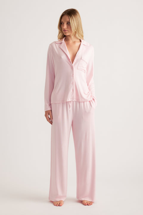 Woman wearing a pale pink button front sleep shirt with wide leg pants