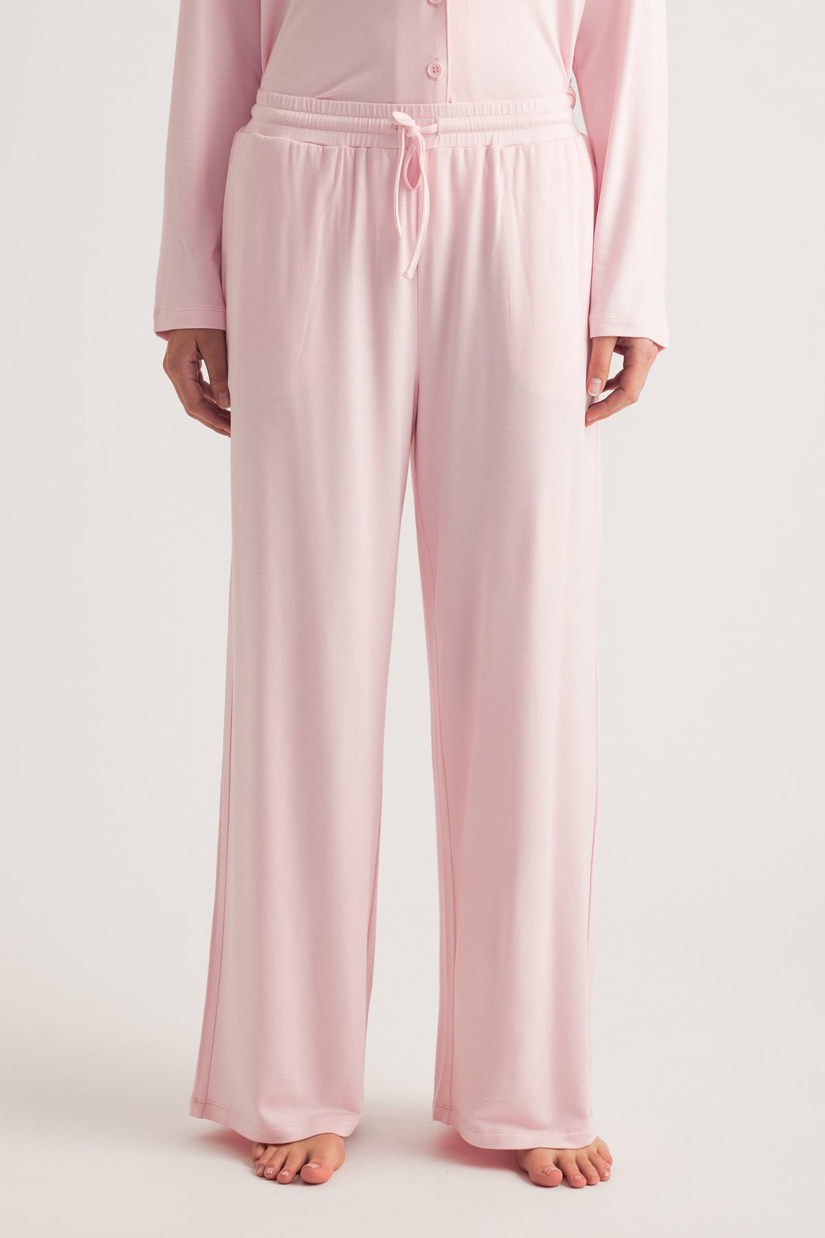 Person wearing pale pink wide leg sleep pants with a drawstring waist