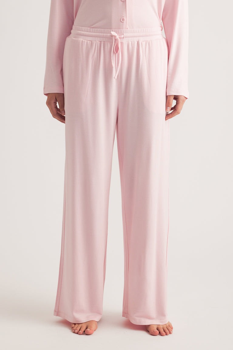 Person wearing pale pink wide leg sleep pants with a drawstring waist