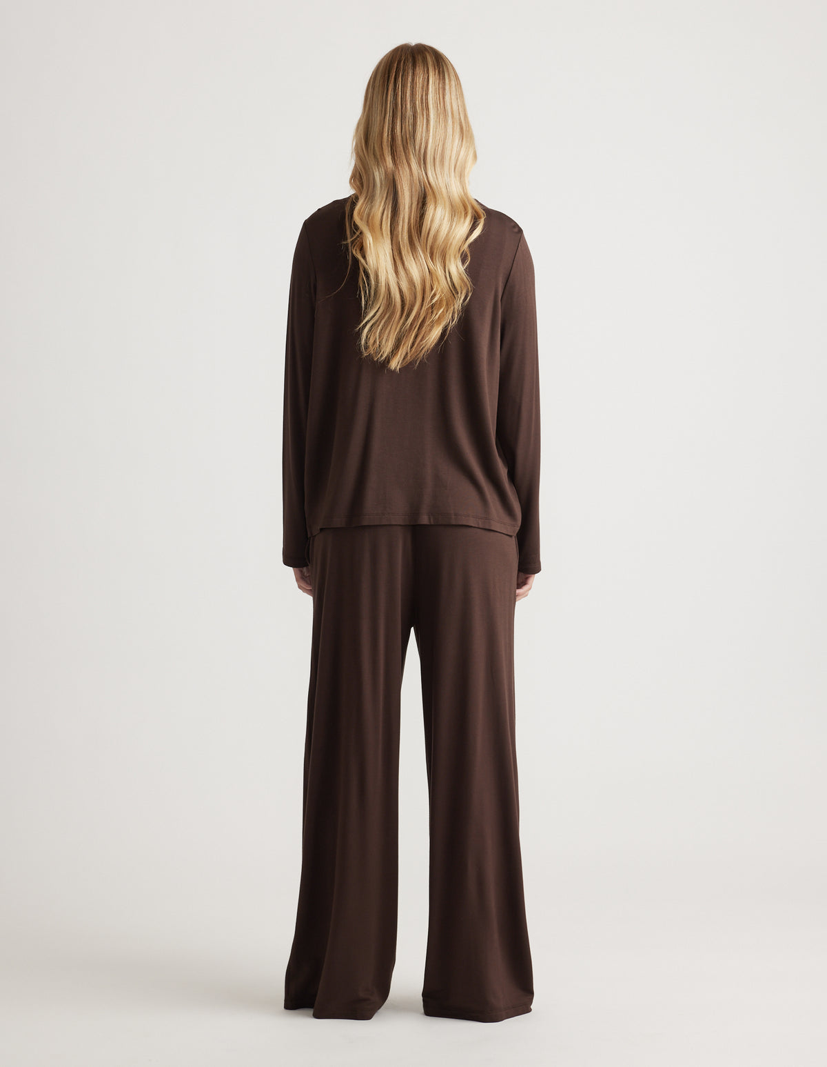 Woman with long loose hair wearing a relaxed chocolate brown lounge set with wide-leg pants from the back view