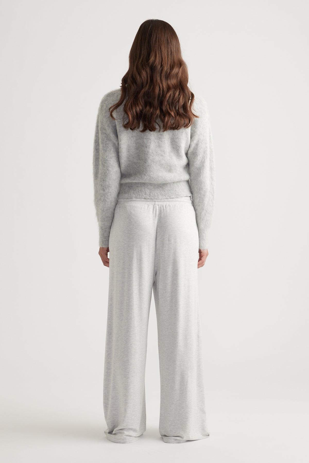 Back view of woman wearing light grey relaxed fit sleep jersey wide leg pants with soft textured sweater