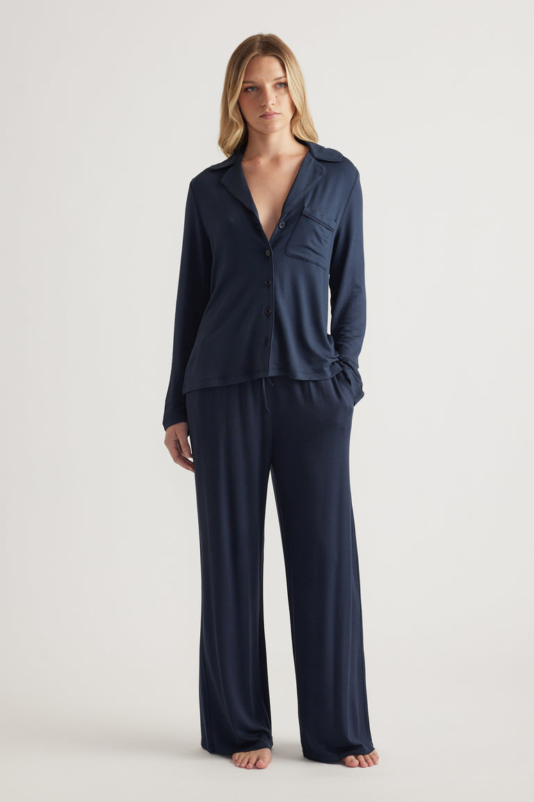 Woman wearing a navy button-up sleep shirt with matching wide-leg jersey pants
