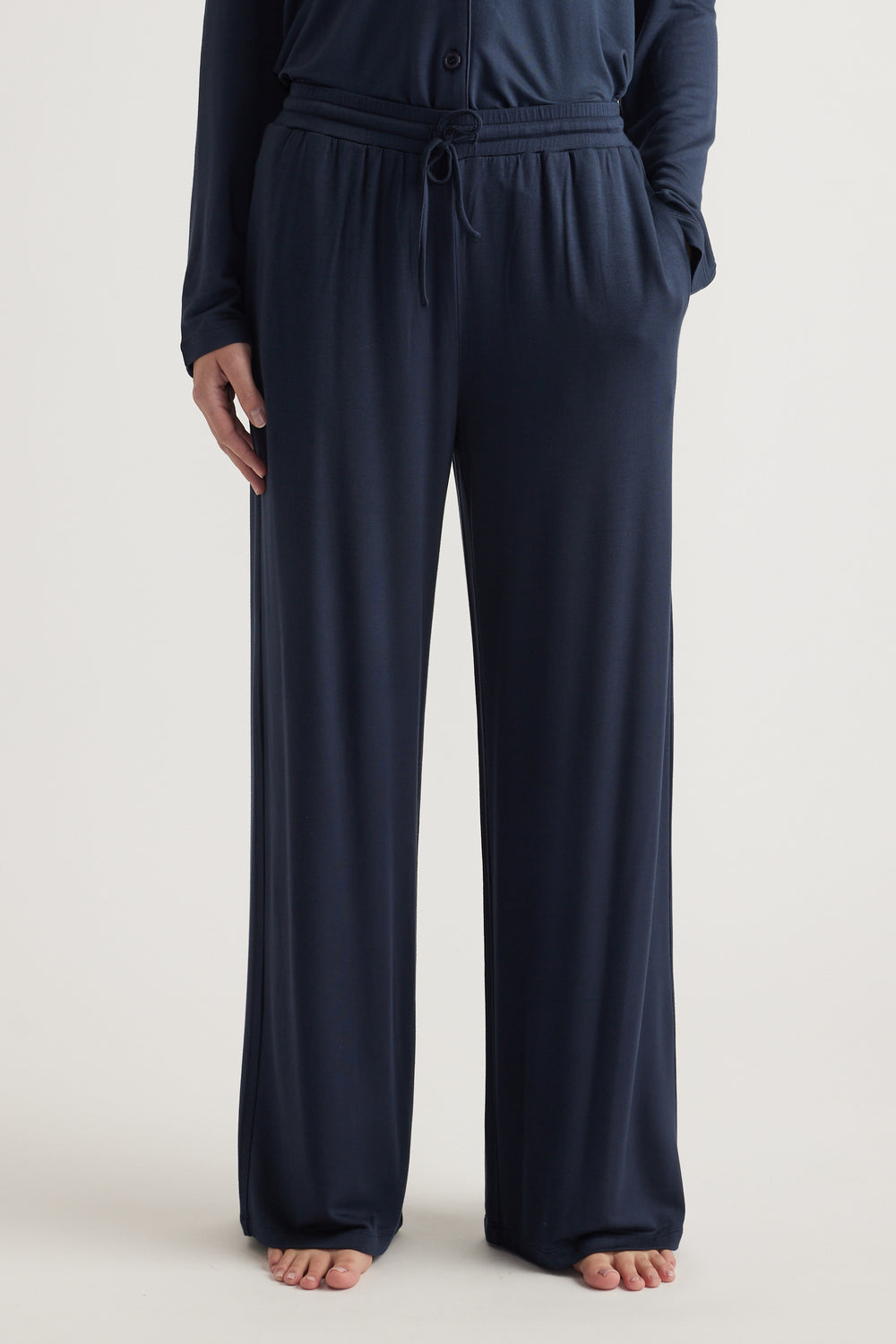 Model wearing navy wide leg jersey pants with an elastic drawstring waist and side pockets