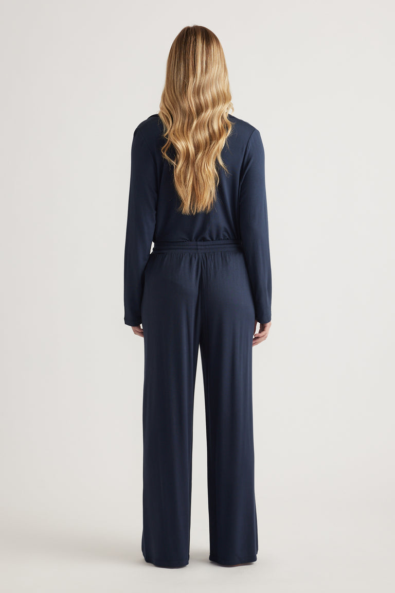 Back view of a woman wearing a navy long sleeve top with matching wide leg jersey pants
