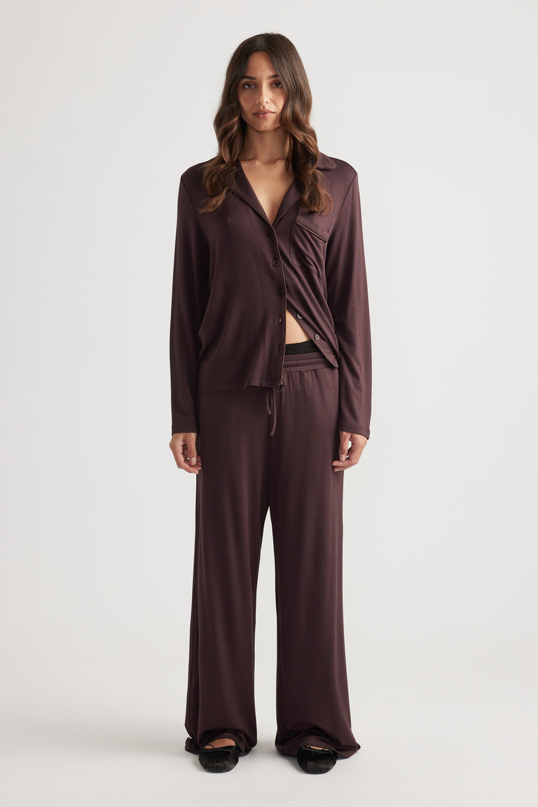 Woman wearing dark rhubarb Sleep Jersey wide leg pants and matching button-up top for cozy, relaxed loungewear style