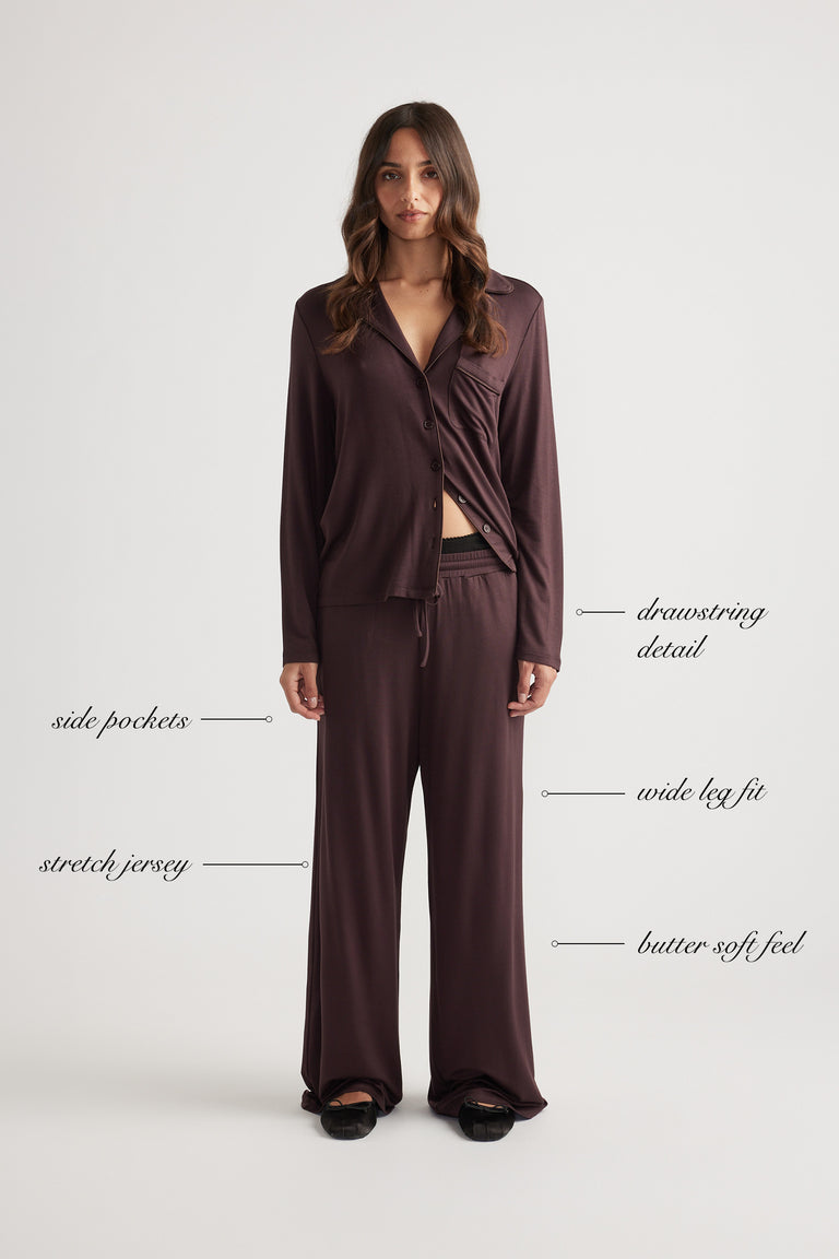 Woman wearing deep burgundy wide leg lounge pants and matching button-up top in soft stretch jersey fabric