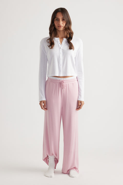 Woman wearing soft pink wide leg pants with drawstring waist paired with a white button-up long sleeve top for relaxed style