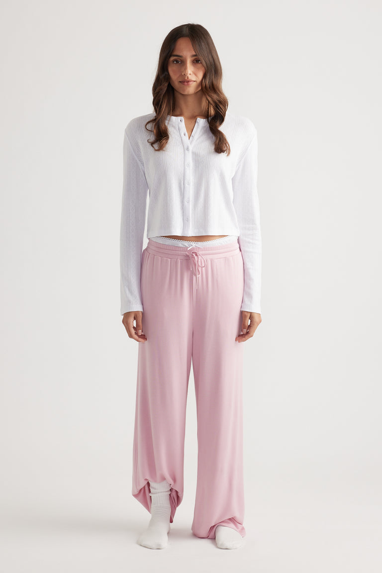 Woman wearing soft pink wide leg pants with drawstring waist paired with a white button-up long sleeve top for relaxed style