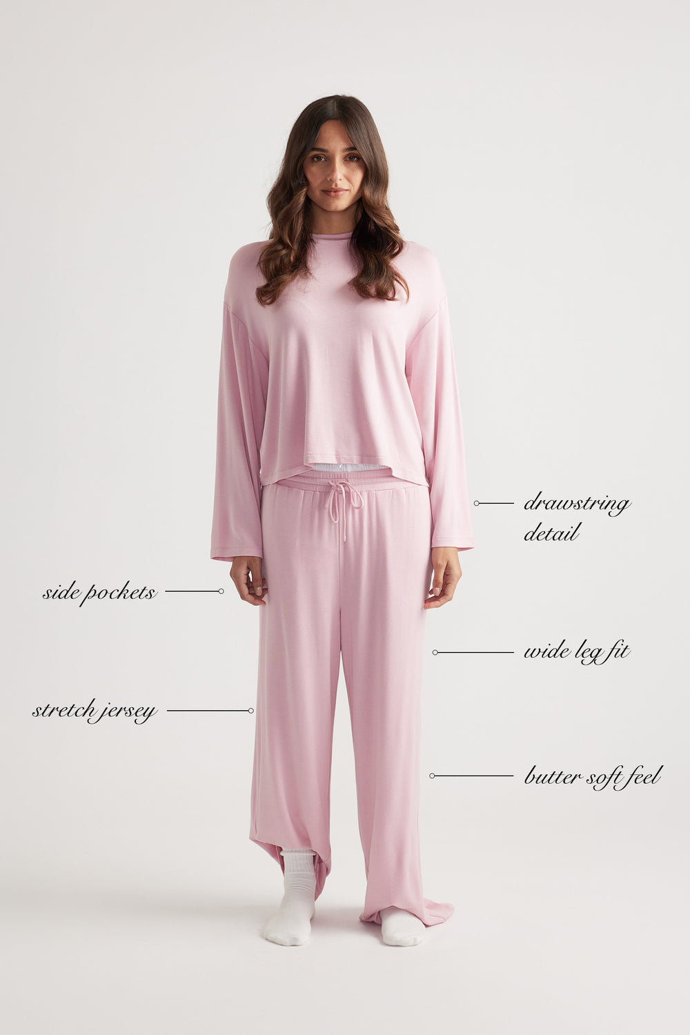 Woman wearing relaxed soft pink wide leg pants with drawstring waist and matching loose long sleeve top in stretch jersey fabric