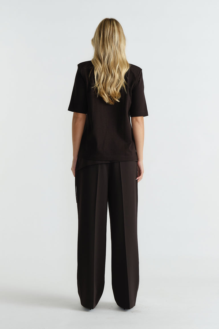 Back view of woman wearing a black shoulder pad tee paired with wide-leg tailored trousers for a polished look.