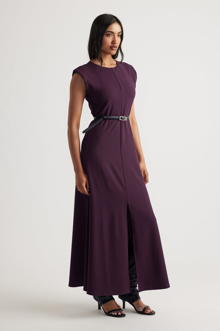Side view of model wearing deep purple Bonnie Shoulder Pad Maxi Dress with black belt and open-toe heels by Decjuba Australian brand