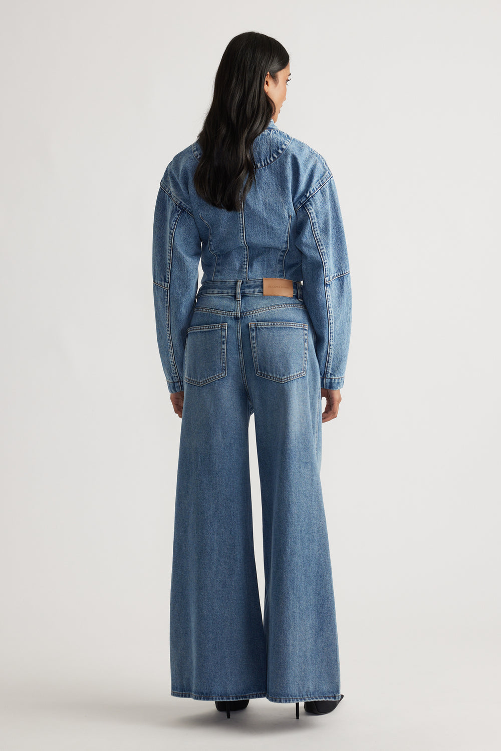 Woman wearing mid-blue wide-leg jeans with high waist and matching cropped denim jacket, viewed from behind