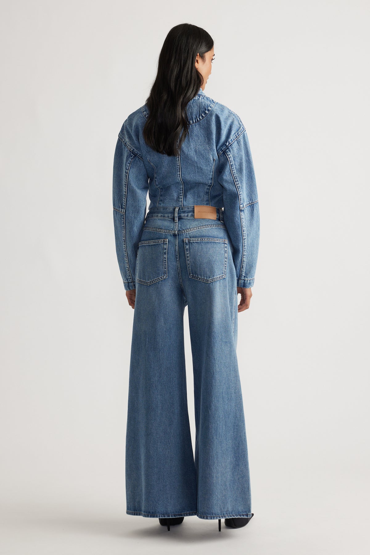 Woman wearing mid-blue wide-leg jeans with high waist and matching cropped denim jacket, viewed from behind