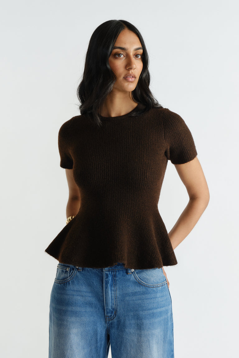 Woman wearing a rich mocha short-sleeve knit top with a peplum hem paired with relaxed fit blue denim jeans