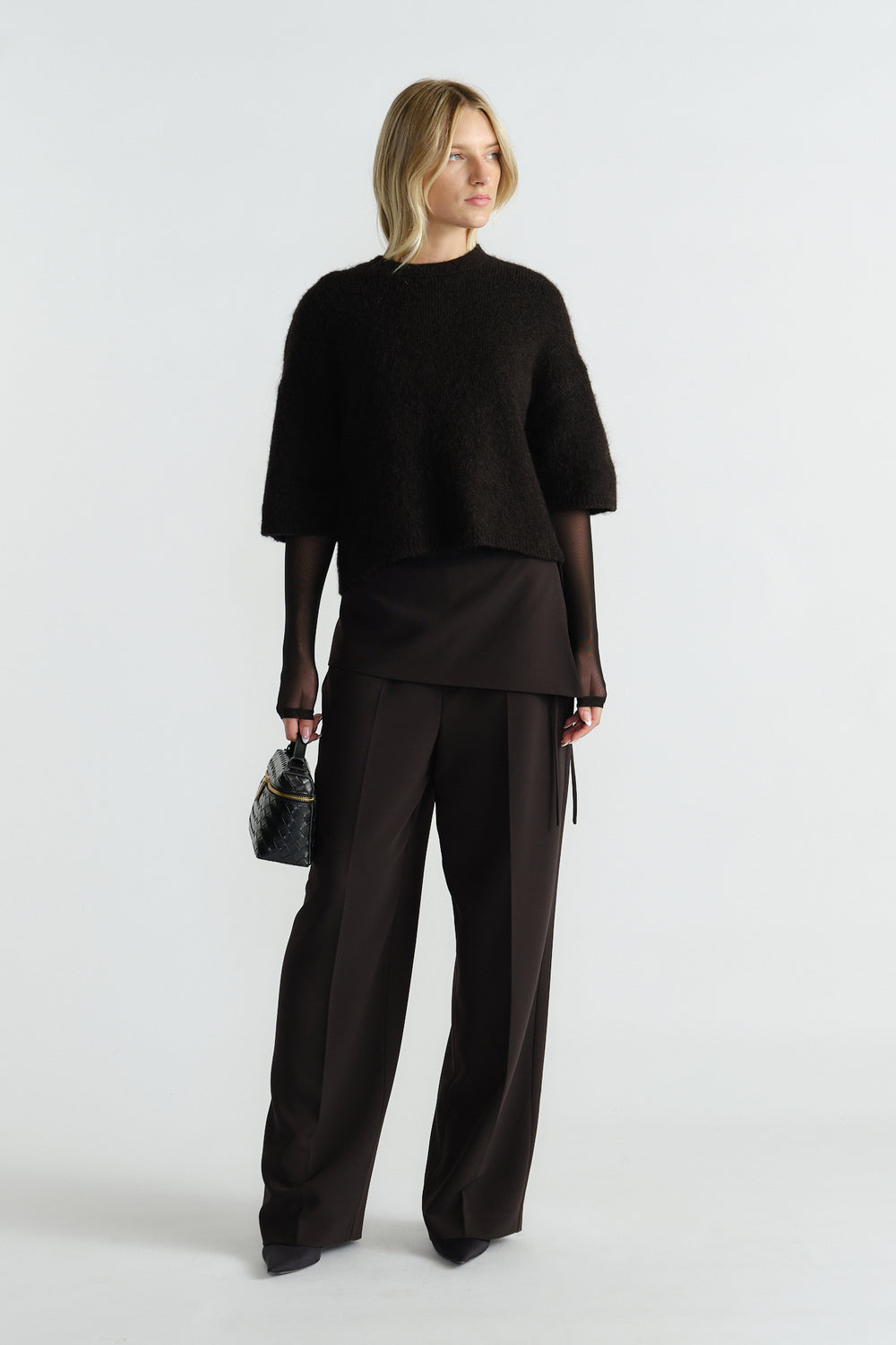 Woman wearing a black fluffy knit tee layered over a sheer long-sleeve top with wide-leg tailored black pants.