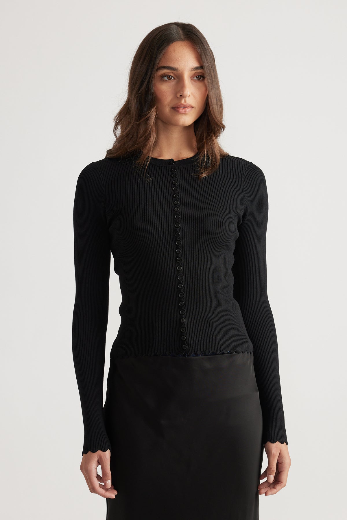Close-fitting black ribbed top with scalloped edges and a row of delicate buttons down the front.