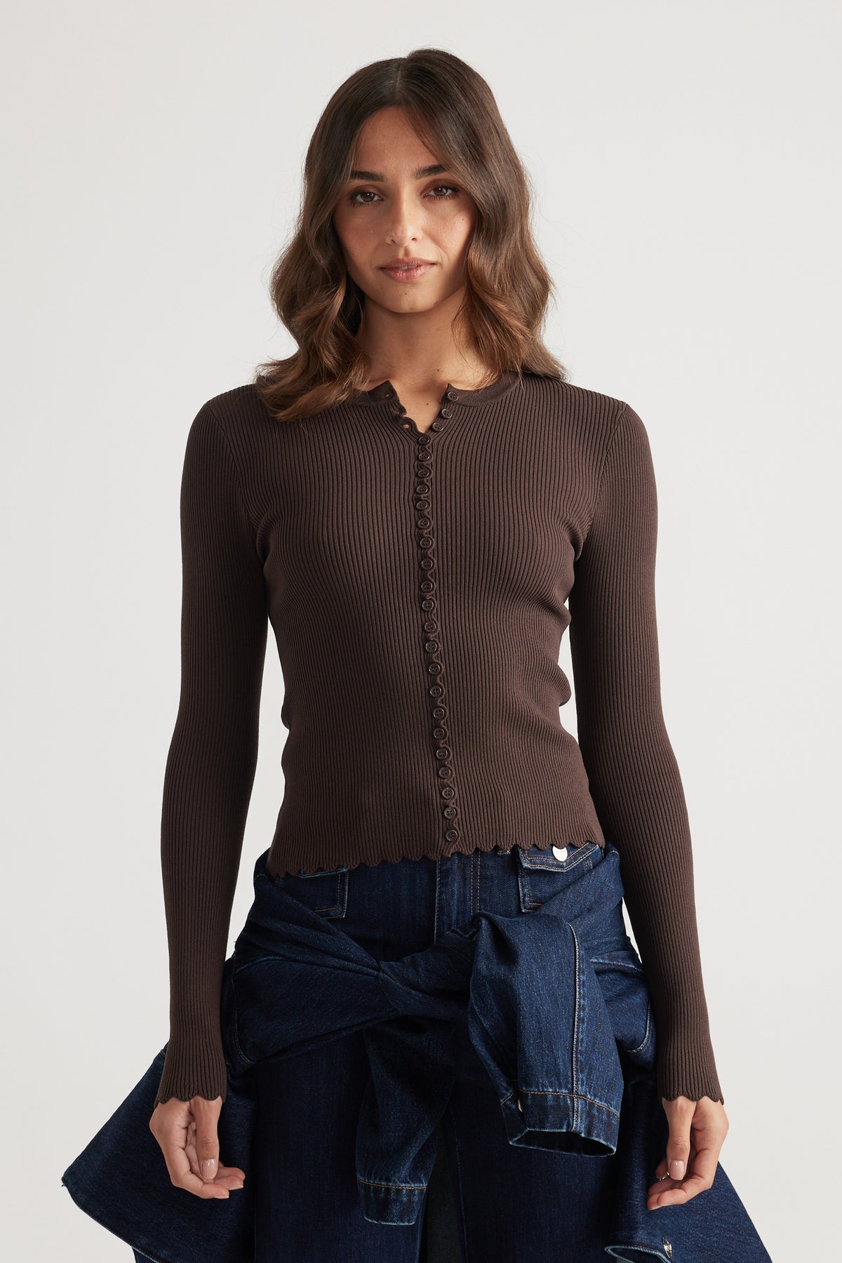 Fitted ribbed mocha top with delicate scalloped edges and button details paired with dark blue denim jeans and jacket tied at waist