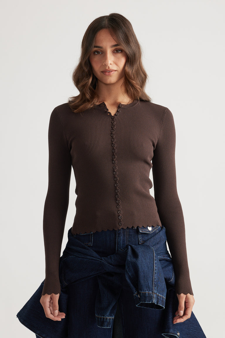 Fitted ribbed mocha top with delicate scalloped edges and button details paired with dark blue denim jeans and jacket tied at waist