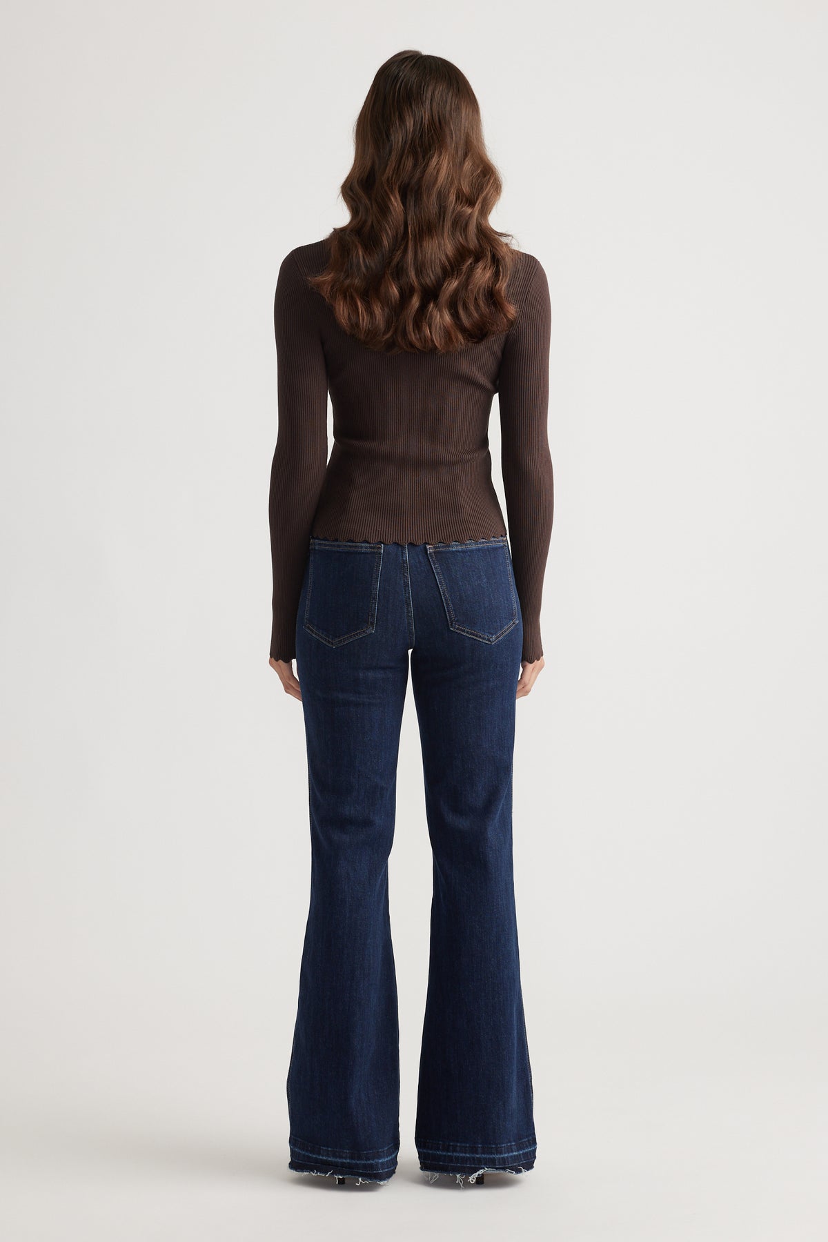 Back view of slim-fit dark brown top paired with high-waisted dark blue flared denim jeans for a sleek casual look