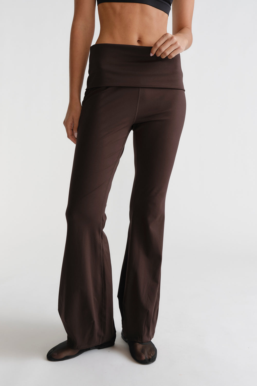Woman wearing cocoa brown D-Luxe Flare Legging with fold-over waistband and relaxed flare silhouette in a sleek fit
