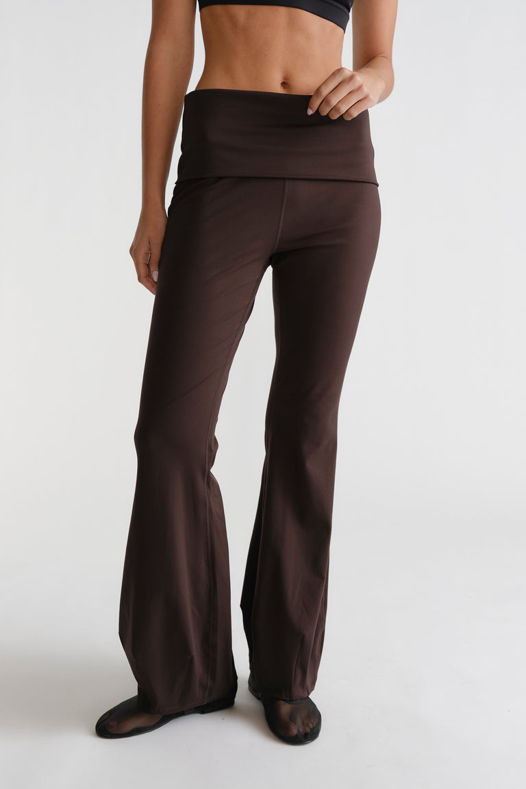 Woman wearing cocoa brown D-Luxe Flare Legging with fold-over waistband and relaxed flare silhouette in a sleek fit