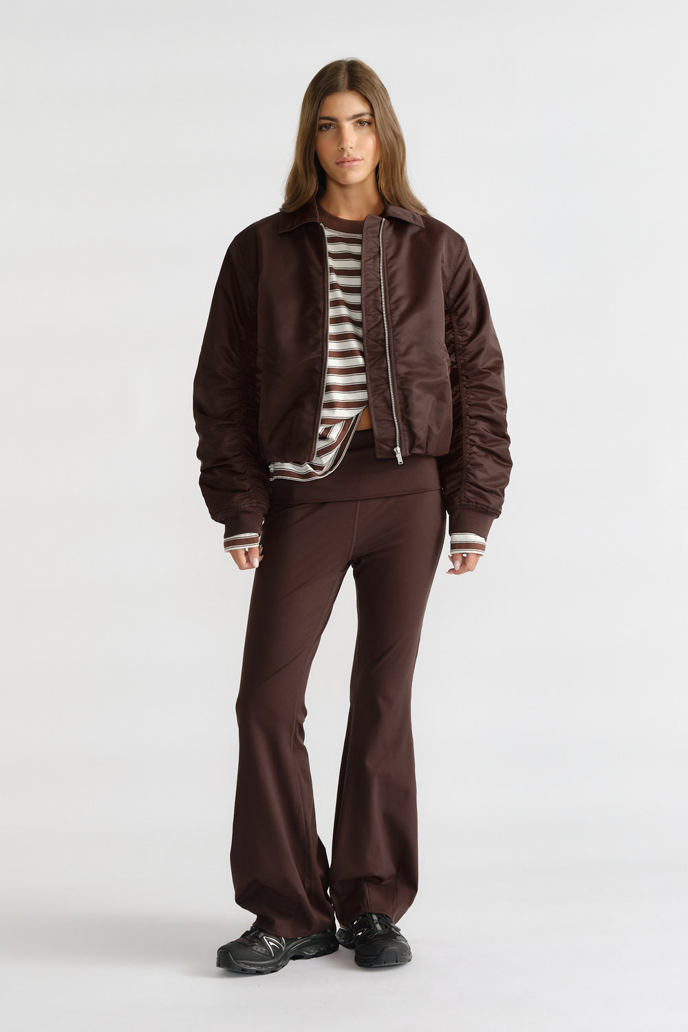Woman wearing D-Luxe Collared Bomber Jacket in rich brown layered over striped top with matching wide-leg pants for casual style