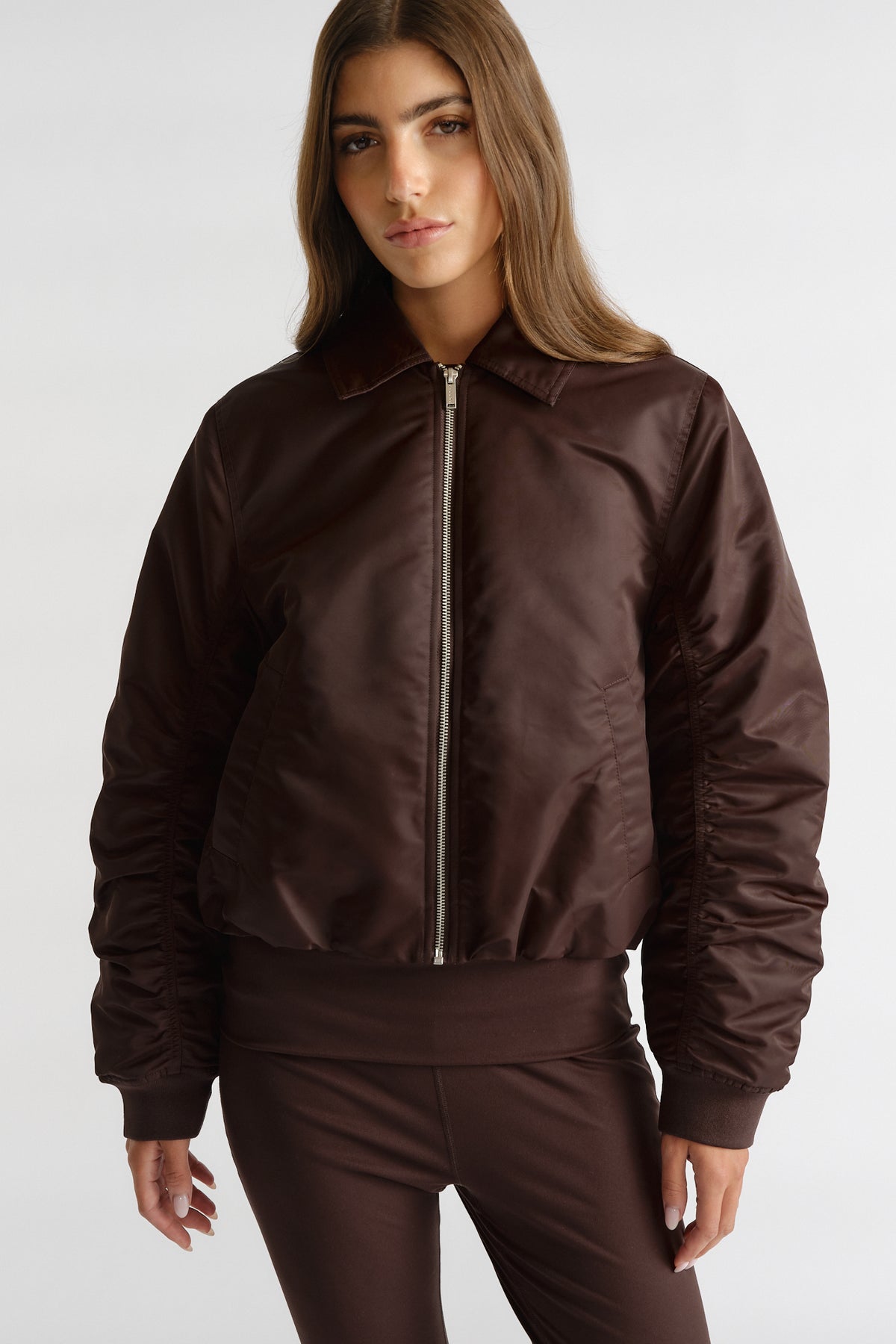 Front view of woman wearing D-Luxe Collared Bomber Jacket in rich cocoa brown with ruched sleeves and matching bottoms