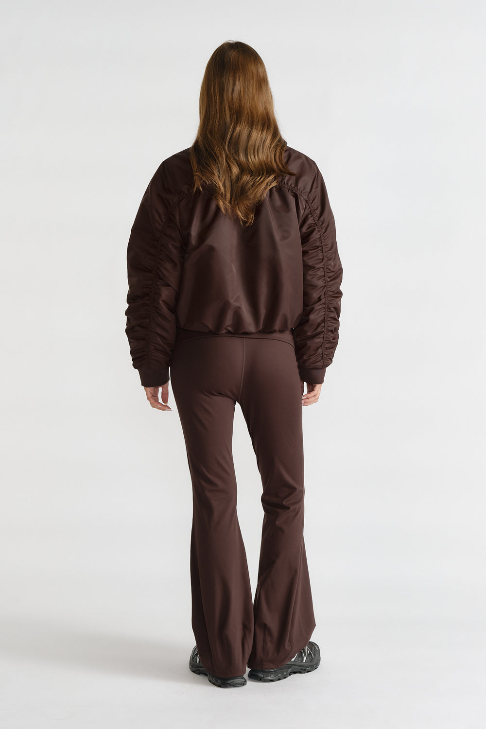 Back view of a model wearing a cocoa brown D-Luxe Collared Bomber Jacket paired with matching flared pants.