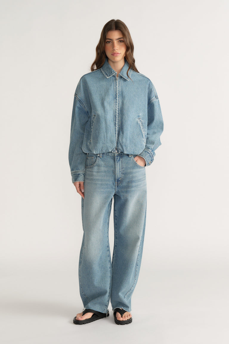 Woman wearing a light wash denim bomber jacket with matching wide-leg jeans and black sandals