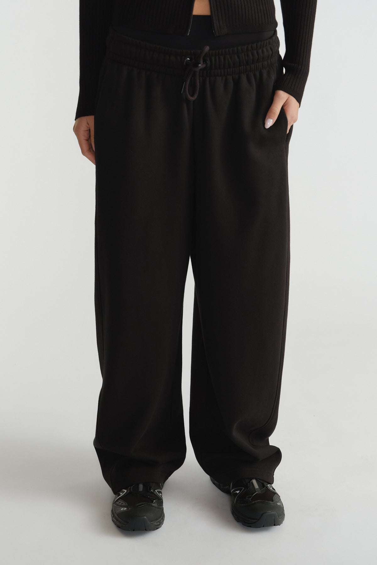 Wide-leg black track pants with elasticated waistband and drawstring, styled with black sneakers and a cropped top