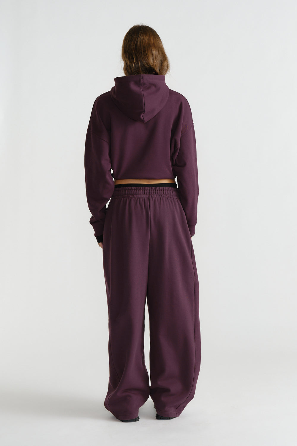 Woman wearing relaxed deep cherry-colored wide-leg track pants paired with a matching cropped hoodie in casual style.