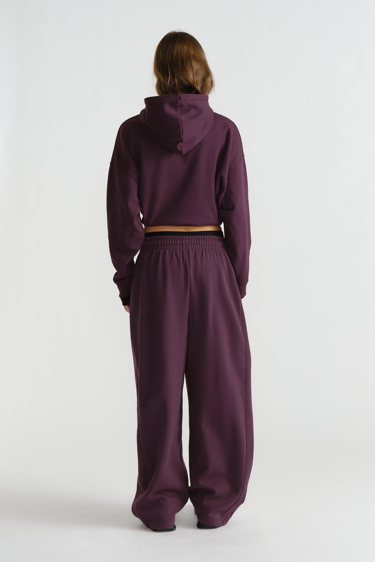 Woman wearing relaxed deep cherry-colored wide-leg track pants paired with a matching cropped hoodie in casual style.