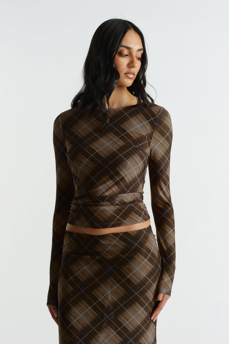 Woman wearing a fitted brown plaid mesh top with subtle blue lines, styled with matching high-waisted skirt.