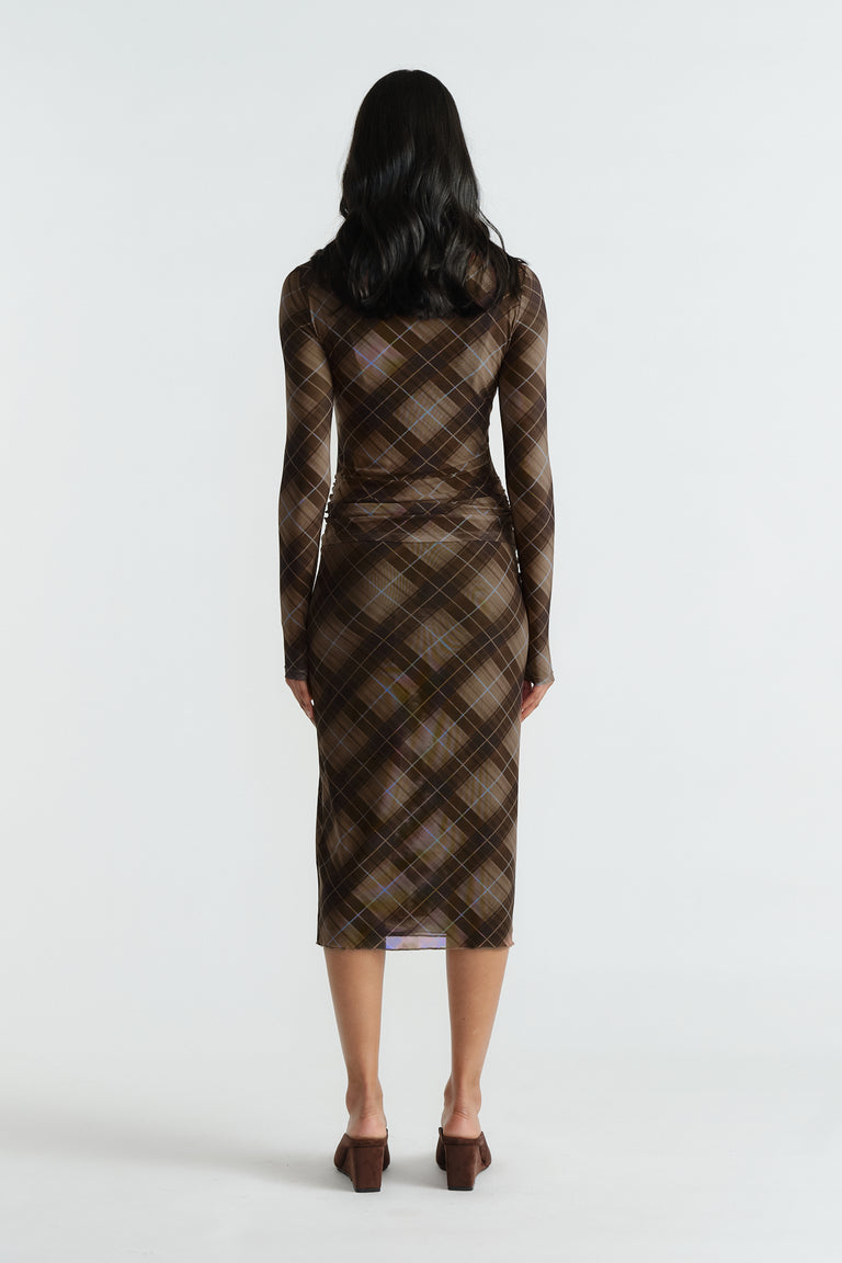 Rear view of woman wearing a fitted brown checked mesh top and matching midi skirt with long sleeves and block heels.