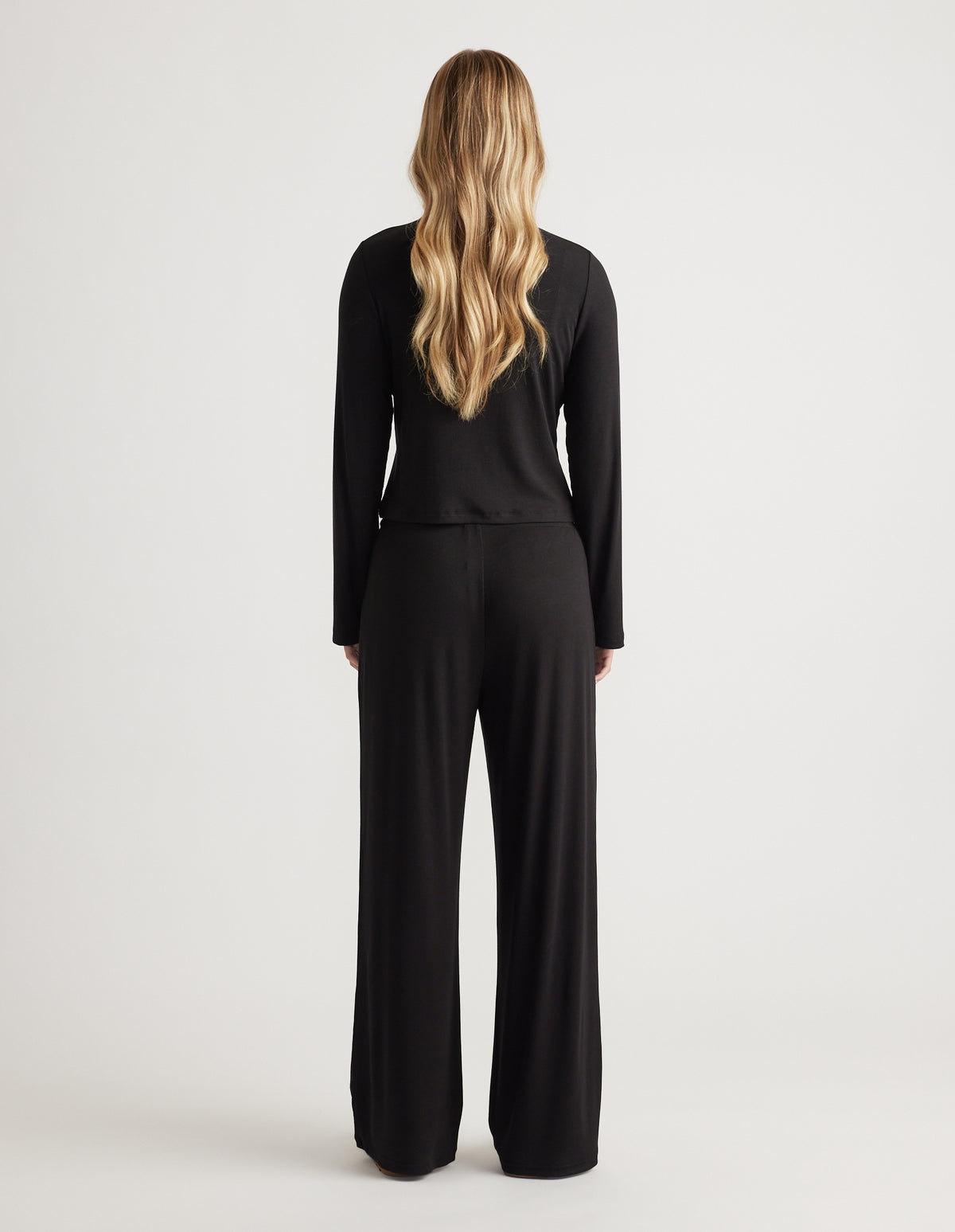 Woman wearing relaxed black ribbed long sleeve top and wide leg pants for a comfortable, versatile loungewear look