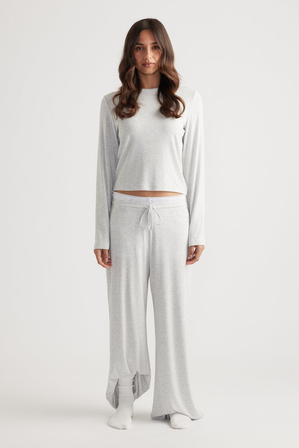 Woman modeling a soft light grey ribbed long sleeve top with a relaxed fit paired with matching wide leg pants