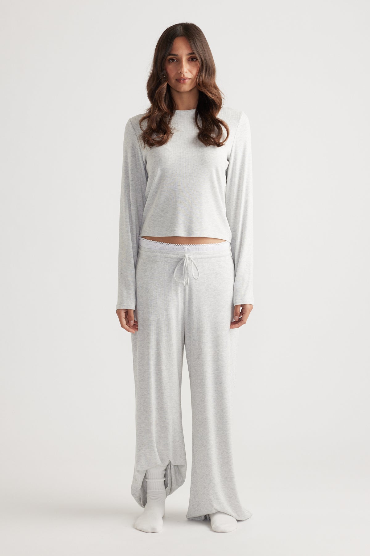 Woman modeling a soft light grey ribbed long sleeve top with a relaxed fit paired with matching wide leg pants