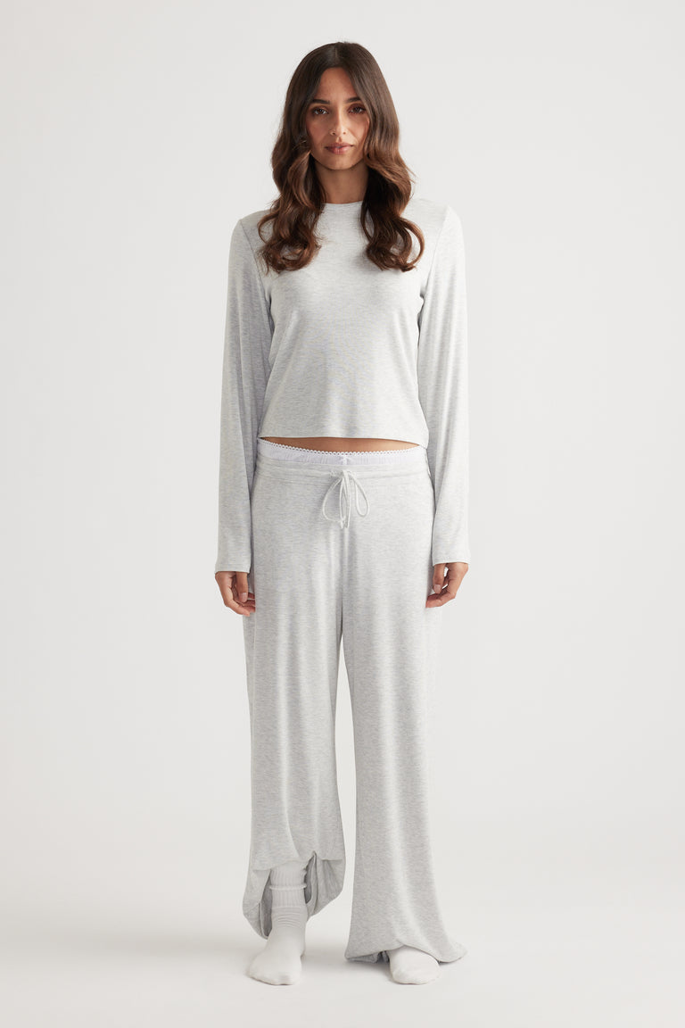 Woman modeling a soft light grey ribbed long sleeve top with a relaxed fit paired with matching wide leg pants