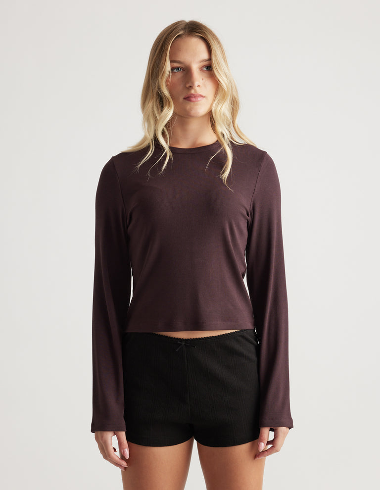 Woman modeling a deep rhubarb ribbed long sleeve top with a relaxed fit and simple crew neckline