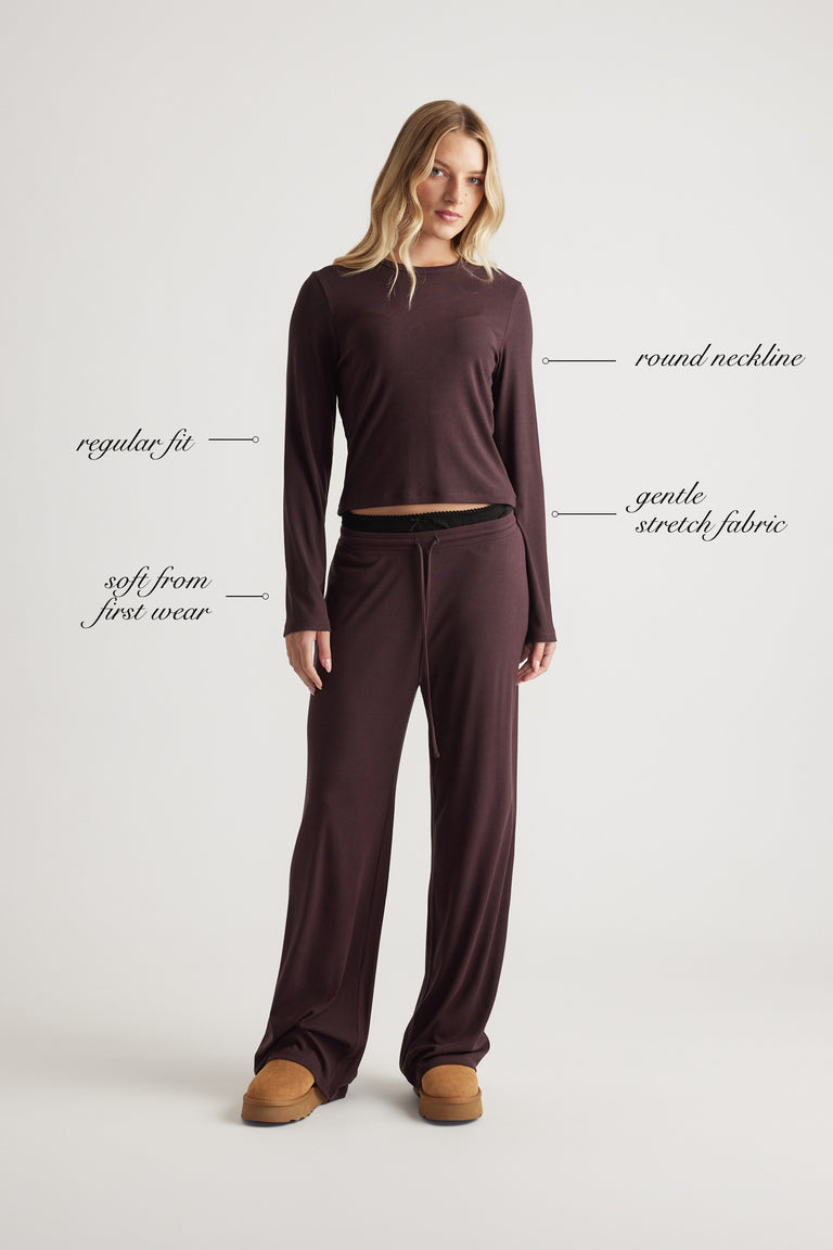 Woman wearing a soft ribbed long sleeve top with round neckline and relaxed fit in a warm rhubarb shade