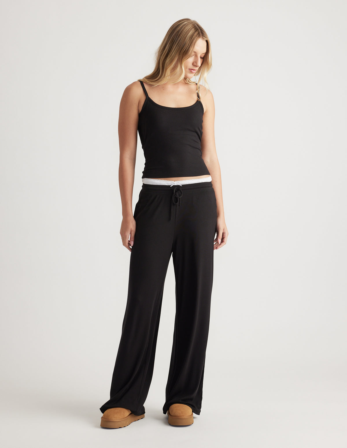 Woman wearing relaxed black ribbed wide leg pants with drawstring waist and a fitted black cami top for casual comfort